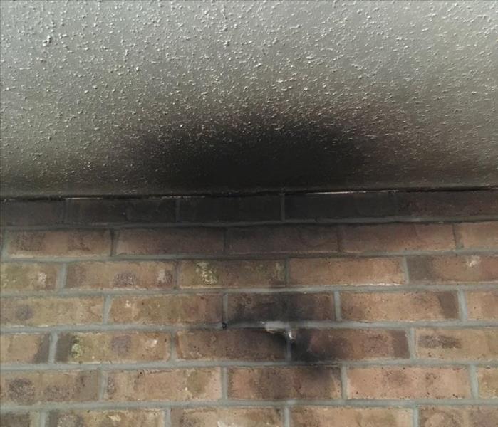 A brick wall and ceiling is black with fire damage.