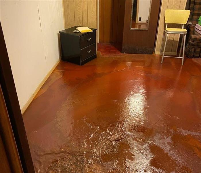 A bedroom floor is covered in water.