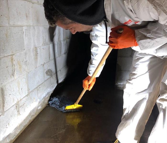 SERVPRO team member mopping a basement floor.