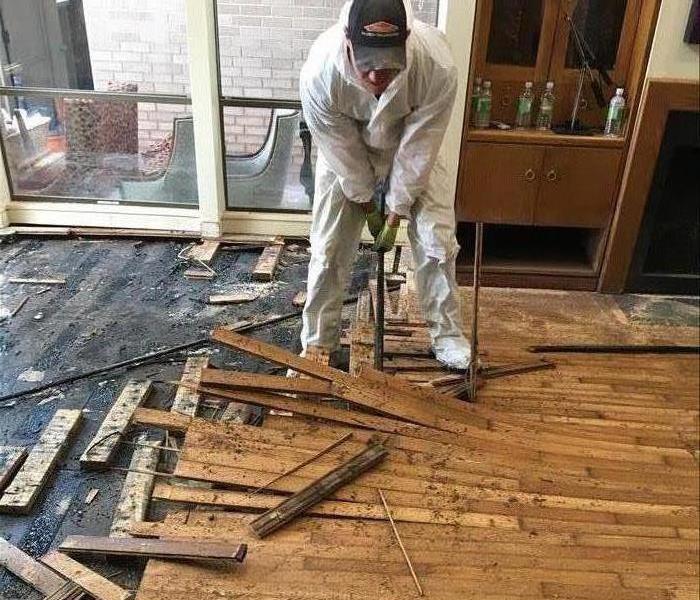 SERVPRO team member is removing a hardwood floor. 