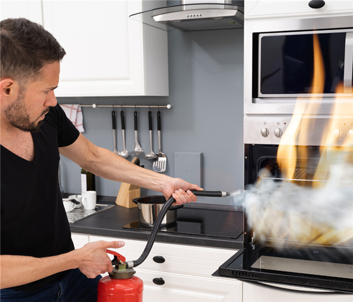 man putting out fire in kitchen